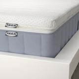 Close-up of ikea mattress; shows pocket springs, textured fabric, and brand labels.
