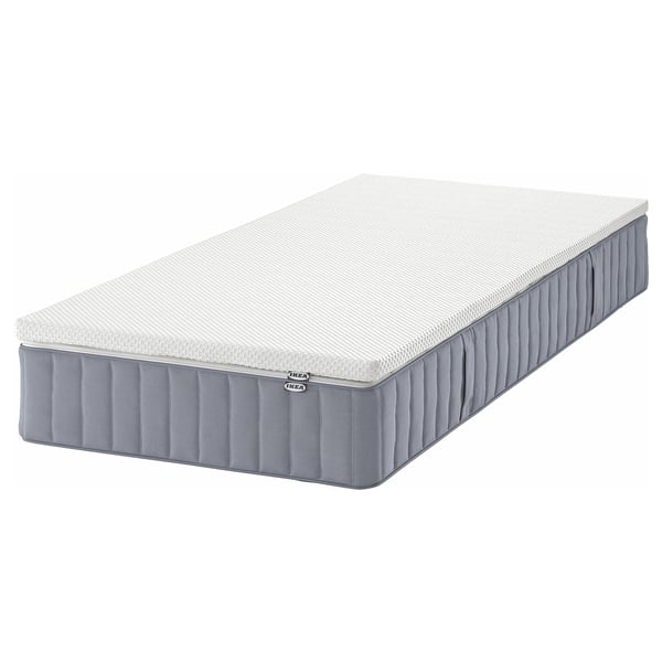 An IKEA VALEVÅG pocket spring mattress in white and grey with a memory foam top, designed for side sleepers or heavier back sleepers.