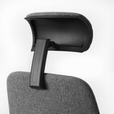 Ergonomic chair detail: adjustable headrest supports neck comfortably. Black upholstery, sturdy armrest.