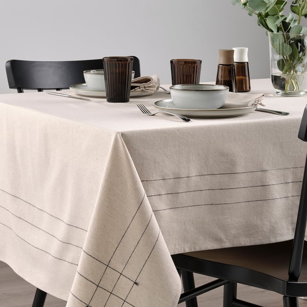 Table set with beige VÅRARV cloth, plates, bowls, glasses, cutlery, and chairs, ideal for seating 4-6 people.