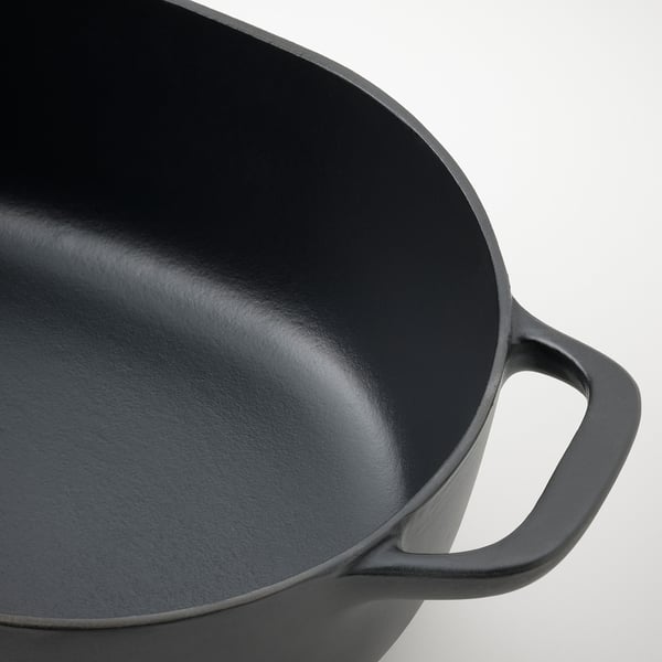 Close-up of black enameled cast iron pan handle, smooth and sturdy, highlighting durable quality.