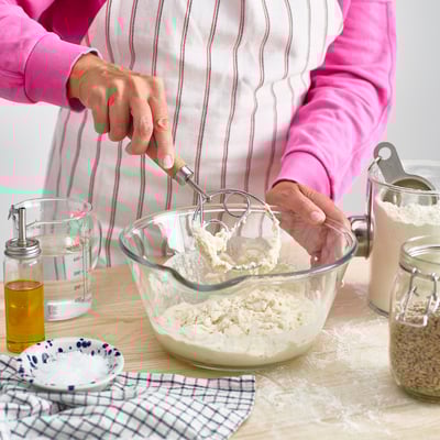 Person mixing dough with danish whisk.