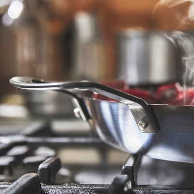 Close-up of robust carbon steel pan handle, designed for easy lifting and heat-resistant use on all stovetops, including induction.