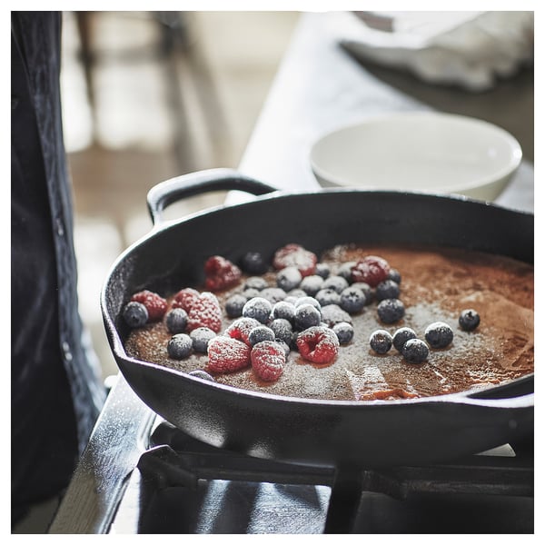 Black cast iron skillet with berries cooking on stove.