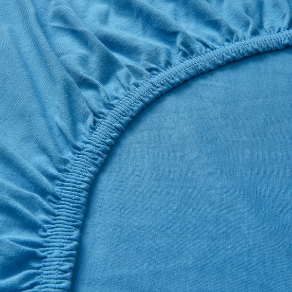 Close-up of soft, blue, jersey-cotton sheet, showcasing fine stitching and smooth texture.