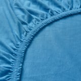 Close-up of soft, blue, jersey-cotton sheet, showcasing fine stitching and smooth texture.