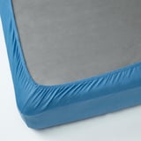 A fitted bedsheet in blue jersey cotton, displaying elastic edges for secure fit.