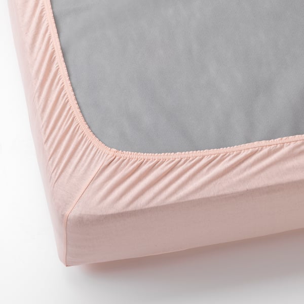 A bed fitted sheet with light pink jersey fabric and elastic edges, perfectly covering the mattress even in corners.