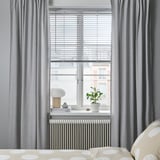 Modern bedroom with VECKLARFLY light gray blinds, polka dot bedding, potted plant, and decor on white radiator.