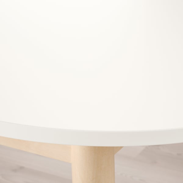 Modern dining table with sleek, matte white top and light wooden legs, evoking a clean and minimalist aesthetic.