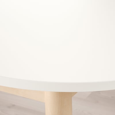 Modern dining table with sleek, matte white top and light wooden legs, evoking a clean and minimalist aesthetic.