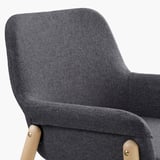Close-up of grey upholstered armchair. High back, curved lines, wooden legs - elegant comfort.