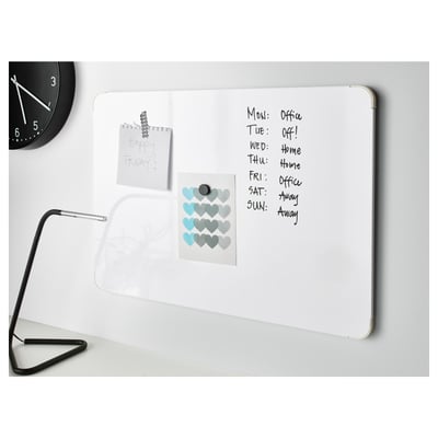 A whiteboard with schedule notes under a clock and lamp, listing days and activities, with stickers and memo.