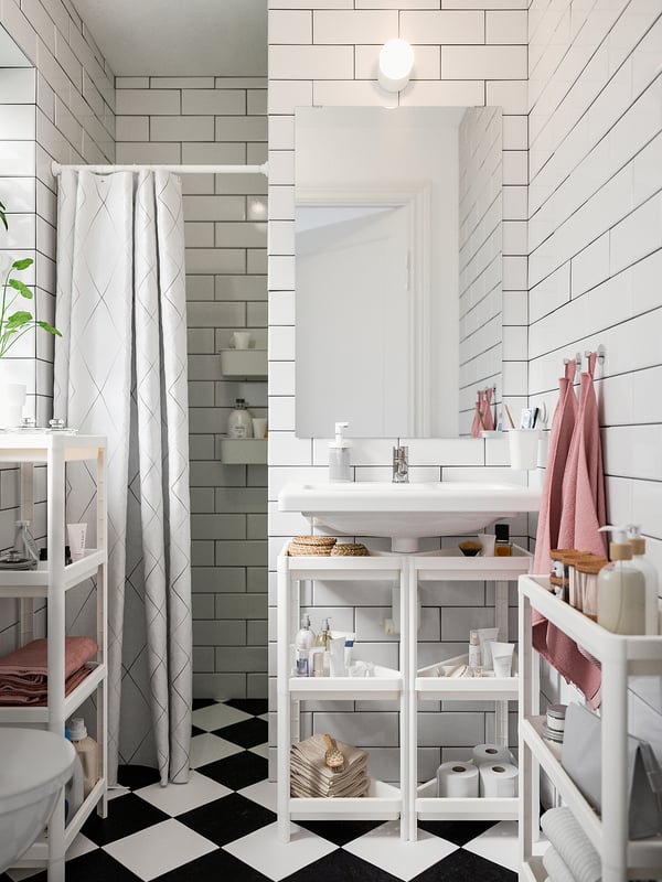 Modern bathroom featuring white VESKEN shelves with various toiletries, grey tiled walls, and a black-and-white chequered floor.