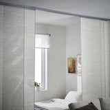 Modern room with VIDGA blinds, white decor, bed, couch, picture frames.
