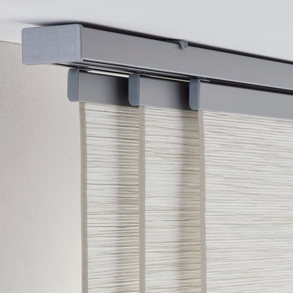 Gray curtain track system mounted on wall with white, vertical blinds.