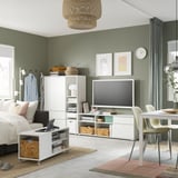 Modern living room with green walls, featuring a white VIHALS tv stand, a cozy bed, and a round rug.