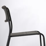 Black woven chair side profile. Curved back and seat with metal frame. Modern design, durable, stackable.