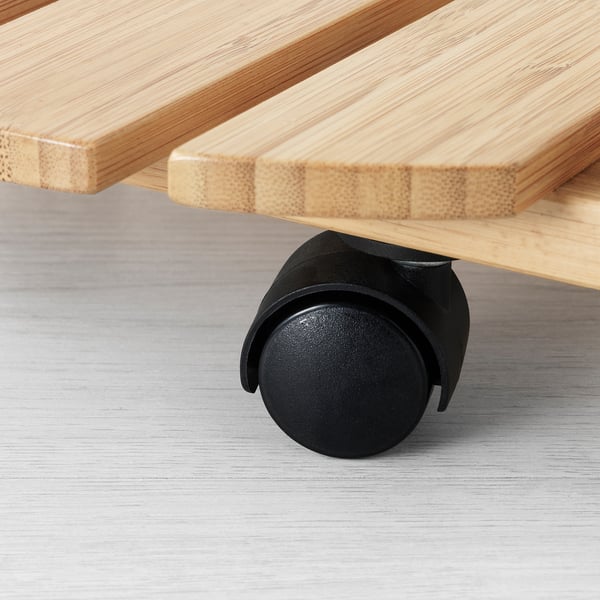 Close-up of a bamboo plant mover with a black wheel. The wheel locking mechanism.