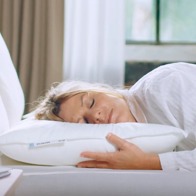 Woman sleeps on white VILDKORN pillow. Rectangular, soft, cotton-polyester blend.