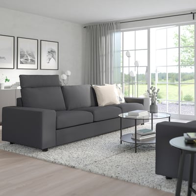 Modern living room with large grey VIMLE sofa, matching armchair, glass coffee table, and rug, set against white walls and large windows.