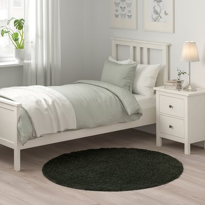VINDEBÄK rug, green, oval, beside white bed, adds warmth & comfort, made from recycled polyester.