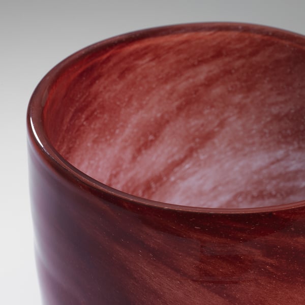 Close-up of a handcrafted glass candle holder, showcasing its rich, reddish-brown hue and smooth, glossy finish.