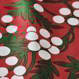 Bright red tablecloth with green leaves and white berries, high quality cotton texture.