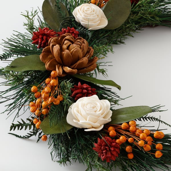 Elegant wreath with pine, orange berries, white roses, and dried flowers.