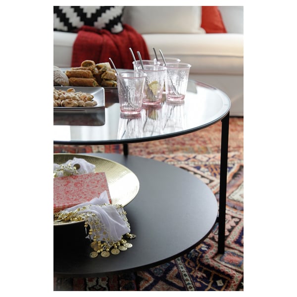 Round glass coffee table with metal frame. Holds drinks and snacks on top, with lower shelf for storage.