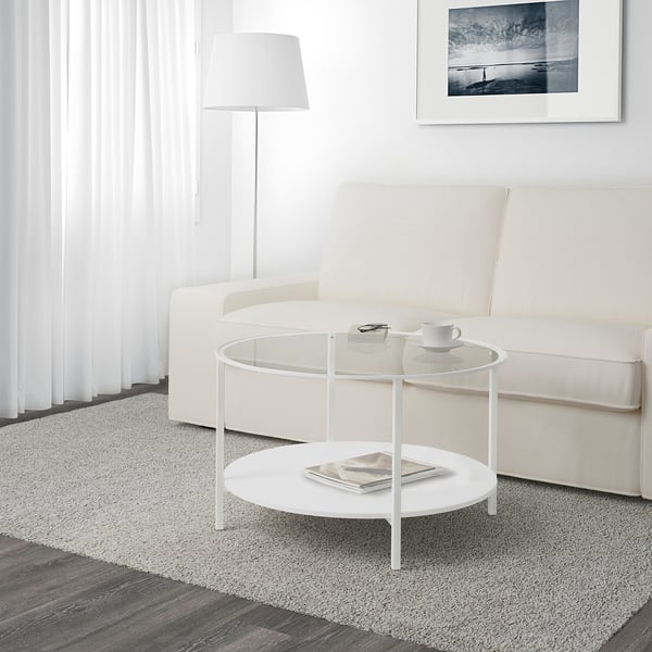 Modern living room with VITTSJÖ glass coffee table, white couch, lamp, and floor rug.