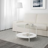 Modern living room with VITTSJÖ glass coffee table, white couch, lamp, and floor rug.