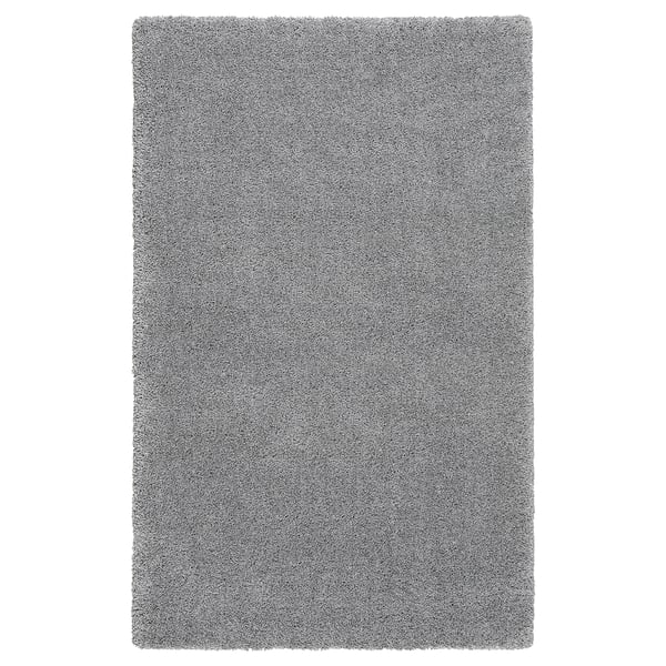 A grey shaggy area rug, rectangular, with varying yarn textures, providing softness and sound dampening.