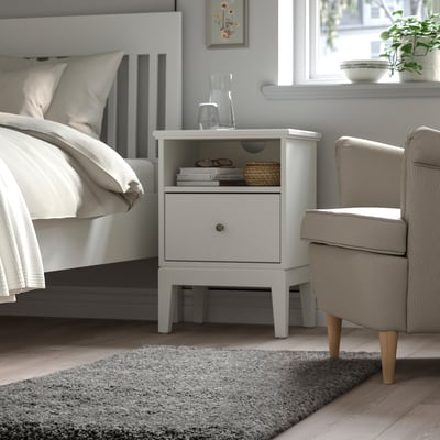 Bedroom with VOLLERSLEV rug, white bed, bedside table, beige chair.