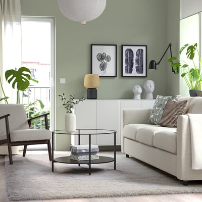 Modern living room with light furniture, plants, VOLLERSLEV rug under sofa and chairs.