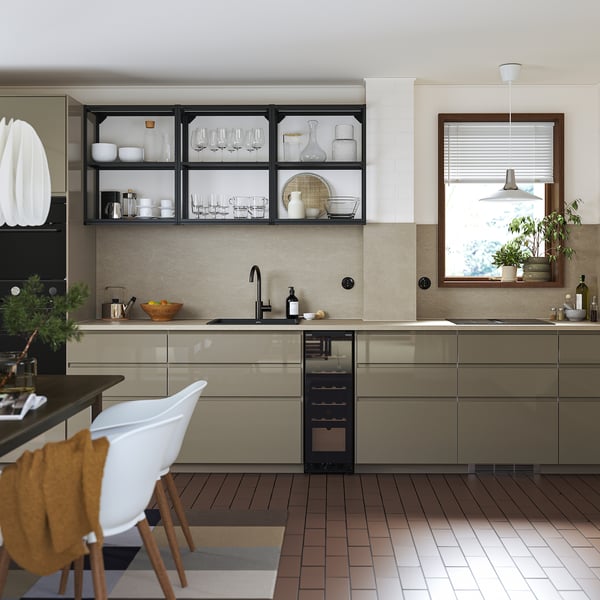 Modern kitchen VOXTORP high-gloss, dark grey-brown cabinet doors with sleek integrated handles, wooden chair, tiled floors, and metallic appliances.