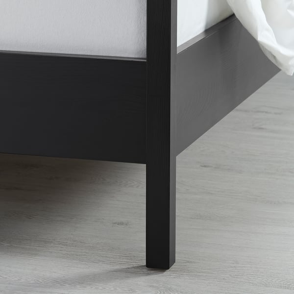 Close-up of a dark wood bed frame corner, showcasing smooth finish and sturdy design.