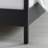 Close-up of a dark wood bed frame corner, showcasing smooth finish and sturdy design.