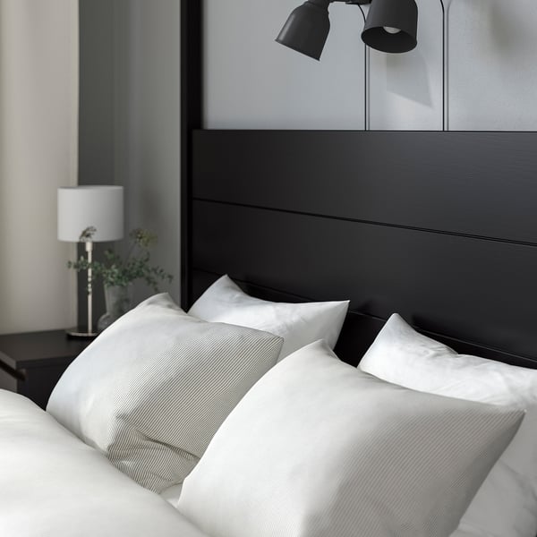 A cozy bed with a tall headboard, crisp white linens, and bedside lamps.