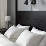 A cozy bed with a tall headboard, crisp white linens, and bedside lamps.