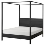 A modern four-poster bed, YTTERVÅG, in dark gray with a solid wood headboard and adjustable sides, perfect for contemporary bedrooms.