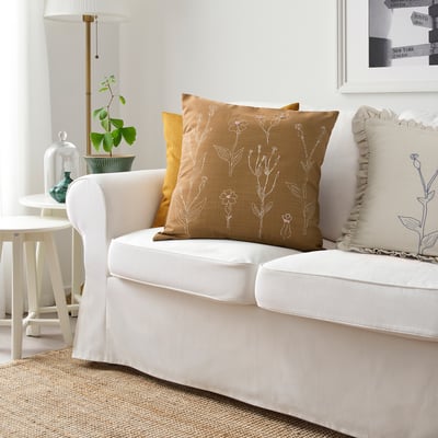 Hyggeligt stuehjørne med hvid sofa, blomsterpude og indretning.