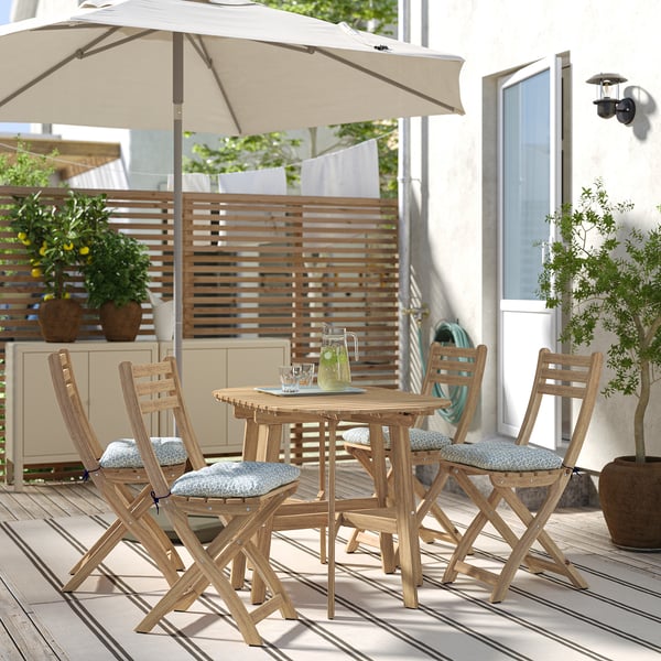 Terrassesæt i træ med bord, fire stole og hynder til kompakte rum.