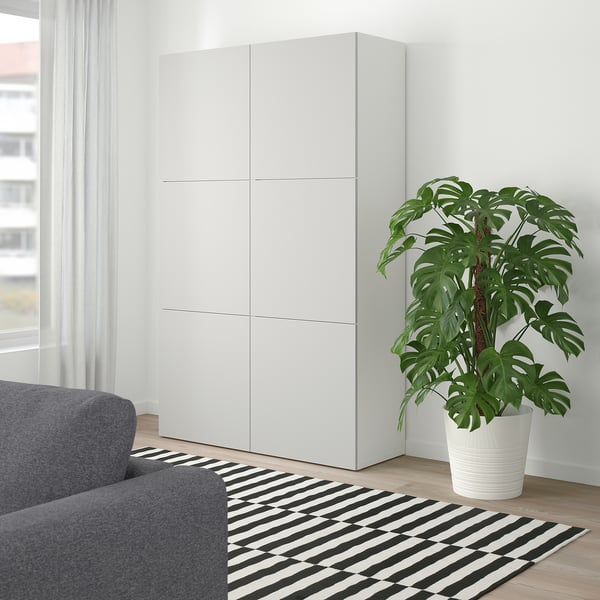 Moderne stue med hvidt BESTÅ-skab, grå sofa og grøn plante.
