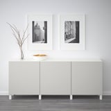 Minimalistisk værelse med hvid BESTÅ-skænk, der viser sort-hvide fotos og en skål med frugt.
