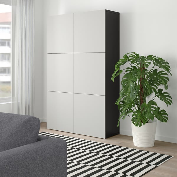 Store, moderne hvide BESTÅ skabstårne i stuen, høje ved siden af grå sofa og stor indendørs plante, med slankt, minimalistisk design.