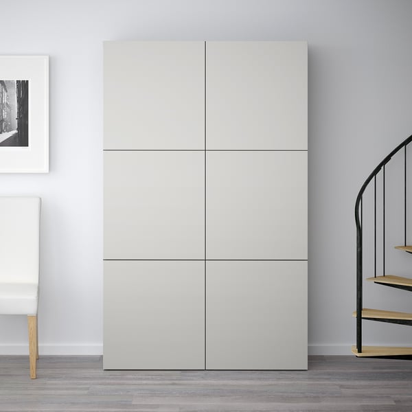 Hvid BESTÅ garderobe står højt, dobbelt så højt som nærliggende stol, med seks firkantede rum, moderne minimalistisk design.