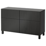 Sort BESTÅ skænk med 4 låger og ben. Moderne, minimalistiske opbevaringsmøbler. Rektangelform med glatte overflader.