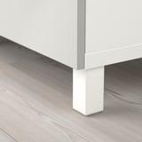 Hvidt tv-stativben på trægulv. Moderne, slankt design med glat finish.