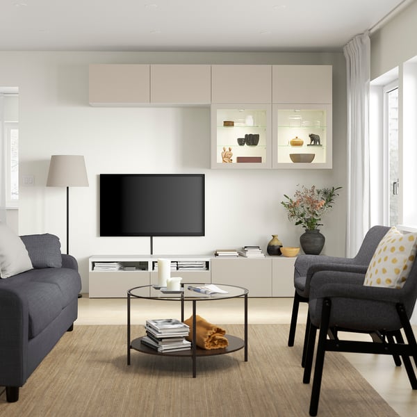 Moderne stue med tv, blå sofa, grå stol, glasbord og overskabe i minimalistisk design.